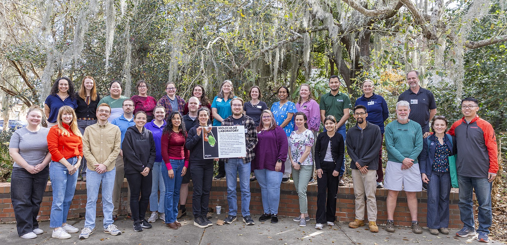 A group of people posing for a photo and holding a sign that reads molecular laboratory